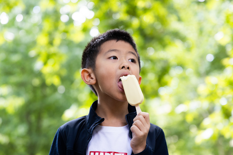 boy eating lolly in front of trees