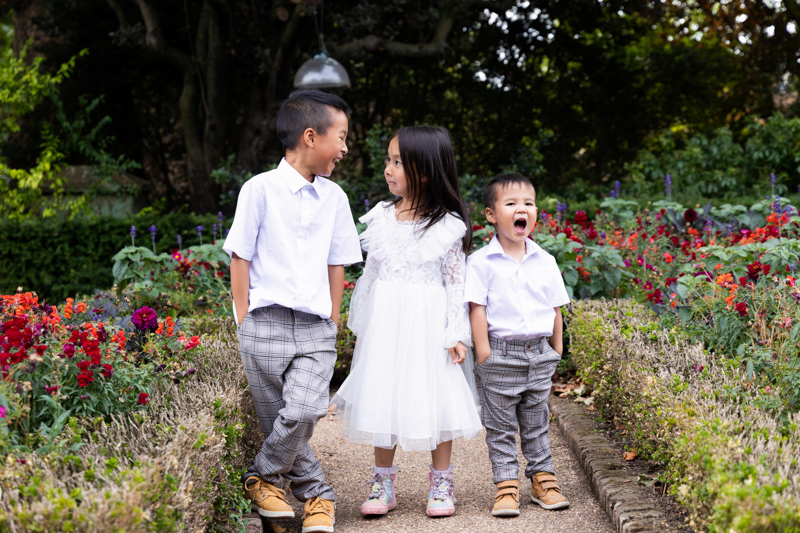 Three children having fun with flowers either side of them. 