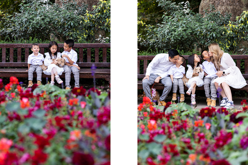 family of five sitting on a bench with flowers in front of them. 