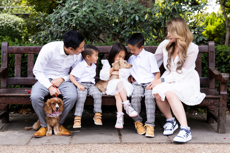 Family of five sitting on a bench with their two dogs