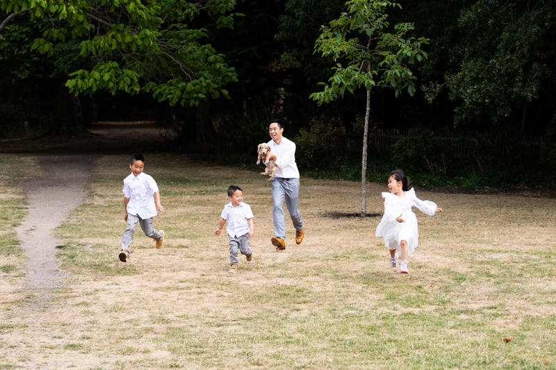 Dad, dog and three children running across the grass