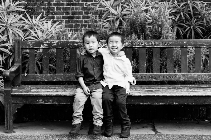 smiling twins sitting on a park bench. 