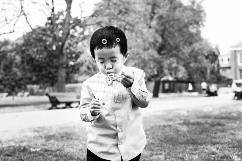 Little boy blowing hard on some bubbles. 
