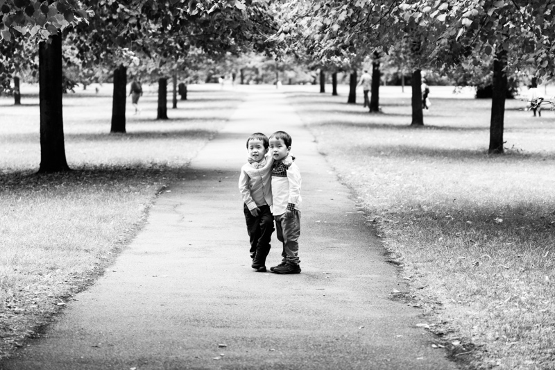 Twin boys standing arm in arm on a path.
