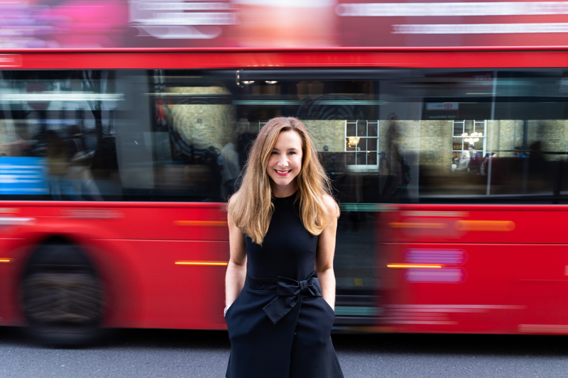 Lady with blurred red London bus in the background. 