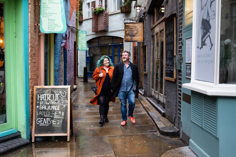 Man and lady walking past colourful shops