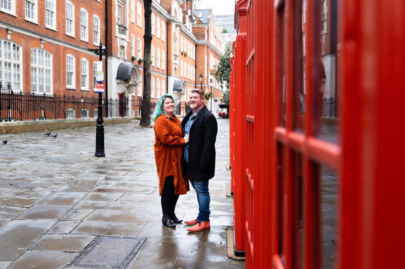 Couple next to a row of red London phone boxes