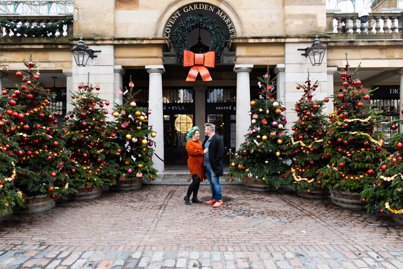 Couple in front of lots of Christmas trees in Covent Garden Market