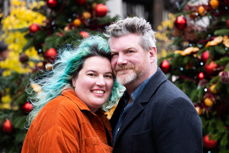 Man and lady smiling in front of Christmas tree
