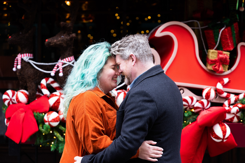Couple with their heads together in front of red decoration