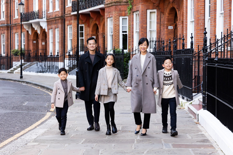 Family of five walking along a street of red brick mansions. 