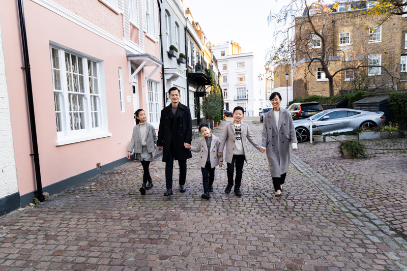 Family walking along a cobbled street past a pink house