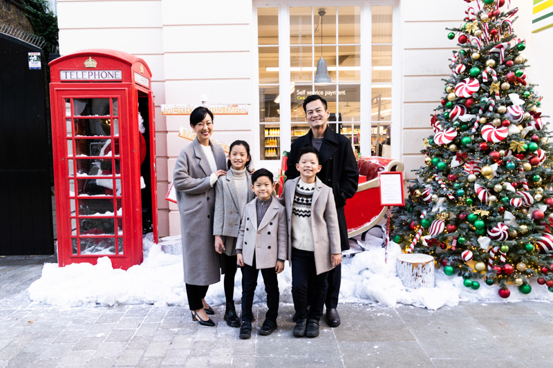 Family of five in front of snowy Christmas scene
