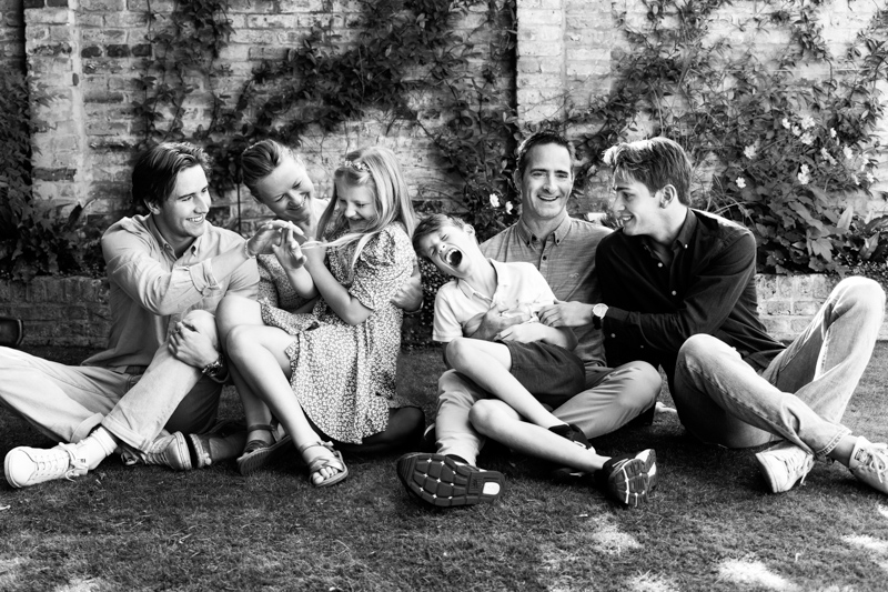 Six members of a family tickling each other on the grass