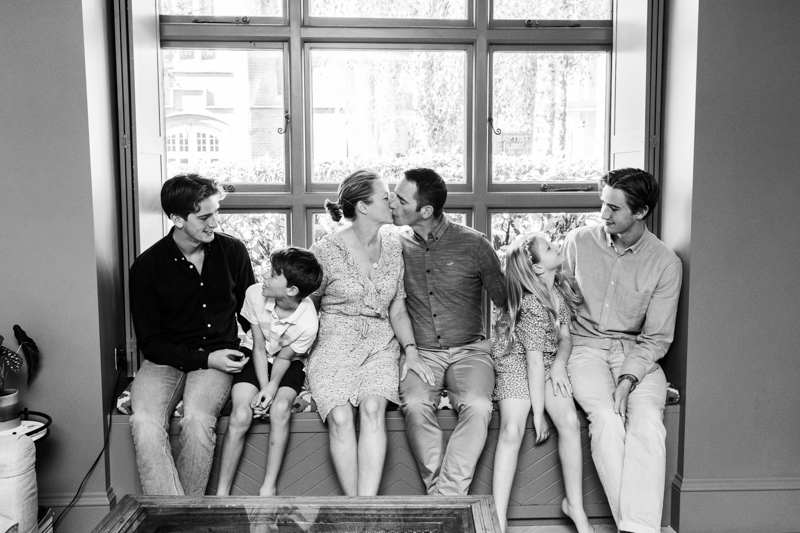 Mum and Dad kissing on windowsill surrounded by children
