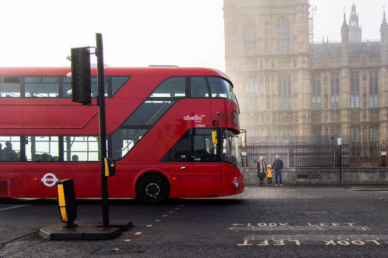 red london bus driving past family and Big Ben
