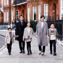 Family of five walking along a street of red brick mansions.