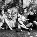 Six members of a family tickling each other on the grass