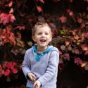 Boy smiling in front of red Autumn leaves