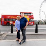 A couple in front of a passing London red bus and the London Eye