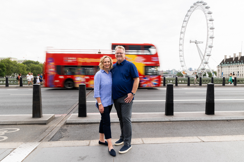 A couple in front of a passing London red bus and the London Eye
