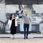 man and lady swinging a little boy in front of a beautiful building