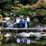 large family group in front of a waterfall, their reflection in the pond in front of them