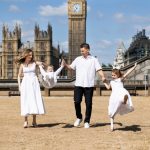 mum and dad with dancing girl and swinging their son, with Houses of Parliament in the background