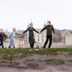 family of four holding hands in front of the Tower of London