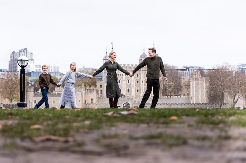family of four holding hands in front of the Tower of London