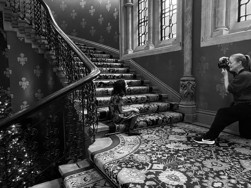 A girl sitting on a staircase with a lady photographing her