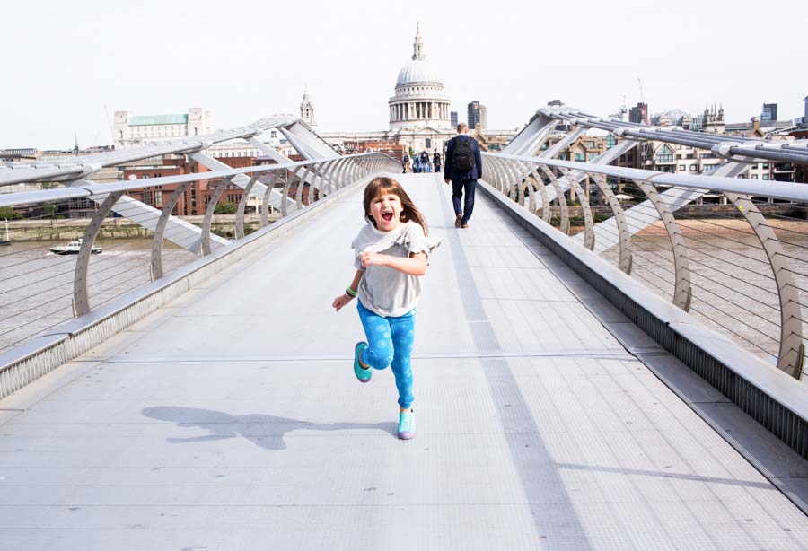 Young girl running across a bridge